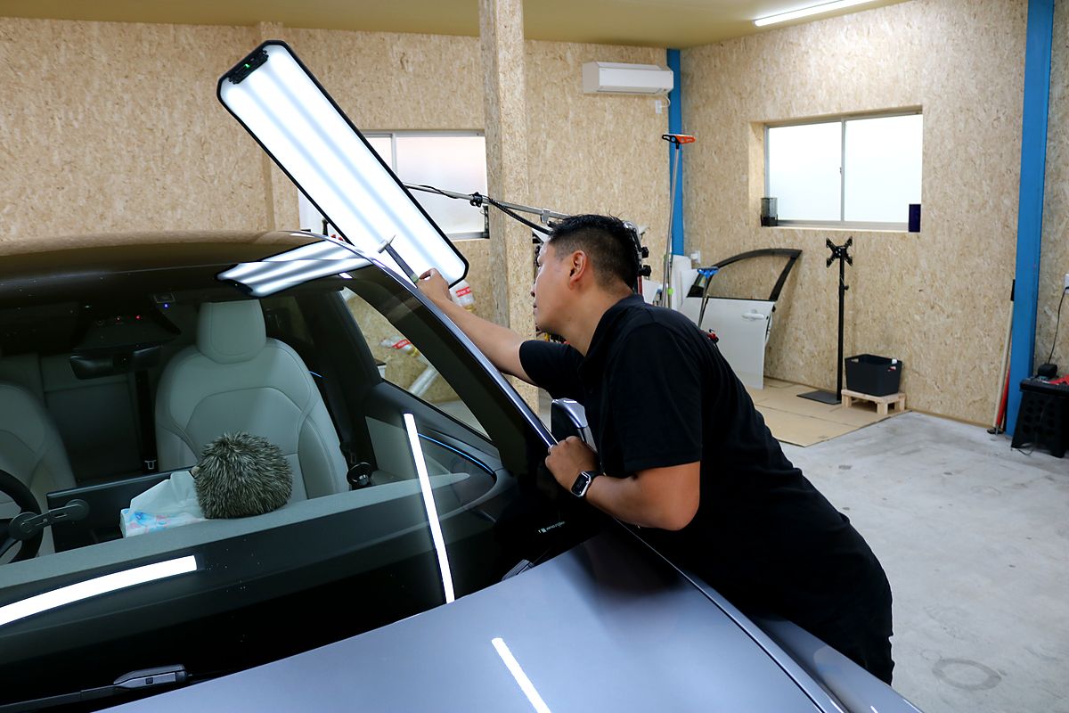 専用ライトの反射でヘコミの形を確認しながら施工しているところ